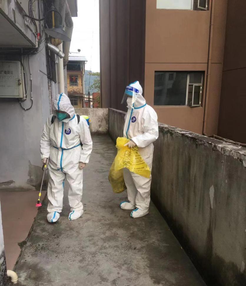 袁登松同志（右）与志愿者在宝利花园小区收集隔离人员生活垃圾后进行消杀.png